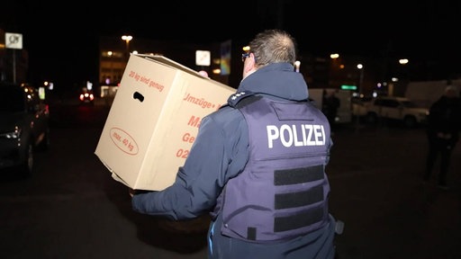 Ein Polizeibeamter trägt einen Karton aus der Sparkassen-Filiale in Gelsenkirchen