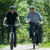 Zwei Männer auf E-Bikes fahren durch den Wald 