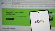 Ein Smartphone mit dem ebay Logo vor dem Hintergrund der ebay Website