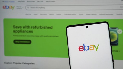 Ein Smartphone mit dem ebay Logo vor dem Hintergrund der ebay Website