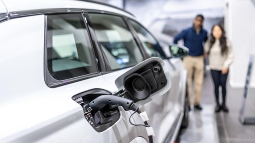 Ein Ehepaar betrachtet ein aufladbares Elektroauto in einem Autohaus