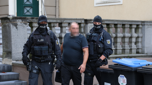 Das Bild zeigt zwei Polizisten und einen Mann, der festgenommen wird