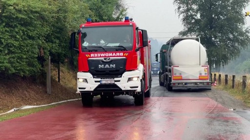 Feuerwehrauto und Lastwagen auf nasser Straße