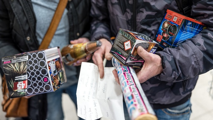 Zwei Personen haben Feuerwerkskörper und eine Einkaufsliste in der Hand
