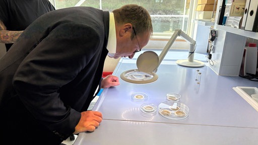 Umweltminister Oliver Krischer beugt sich über Exponate
