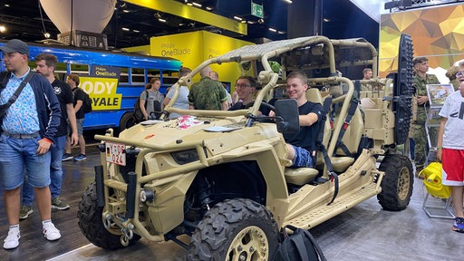 Zwei Jungs sitzen in einem Leichten Luftlandefähigen Utility Terrain Vehicle am Bundeswehrstand 
