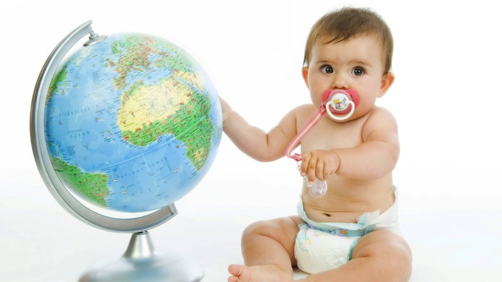 Ein Baby sitzt neben einem Globus.