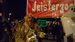 Ein verkleideter Mann vor einem Banner mit der Aufschrift "Jeisterzoch"