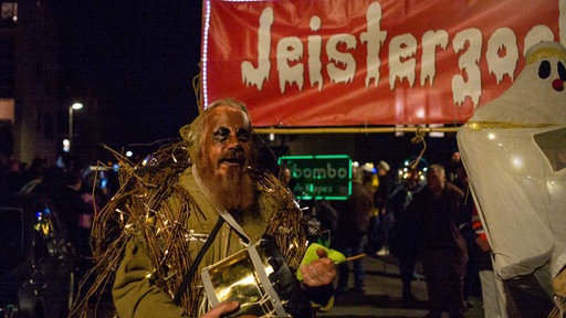 Ein verkleideter Mann vor einem Banner mit der Aufschrift "Jeisterzoch"