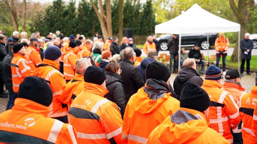 Hunderte Straßenwärter stehen gemeinsam mit roten Warnwesten vor der Gedenkstätte
