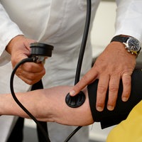 Ein Hausarzt misst in seiner Praxis einer Patientin den Blutdruck.