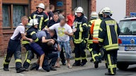 Drei Männer behindern nach einem Unfall die Arbeit der Rettungskräfte.