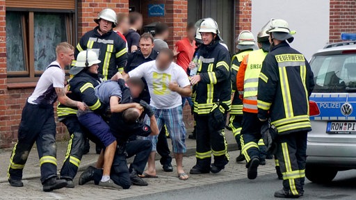 Drei Männer behindern nach einem Unfall die Arbeit der Rettungskräfte.