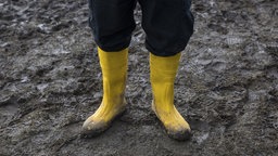 Gelbe Gummistiefel im Matsch
