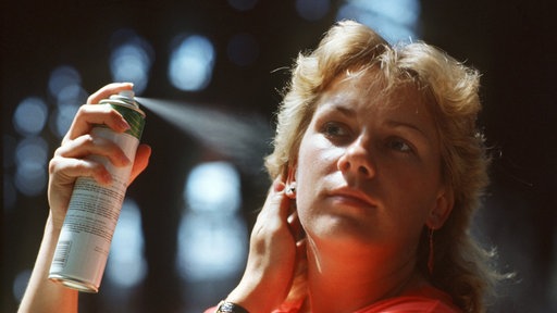 Eine junge Frau sprüht sich Haarspray auf ihre Frisur. (Aufnahme vom Juni 1985).