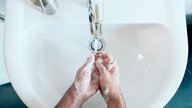 eingeseifte Hände über einem Waschbecken