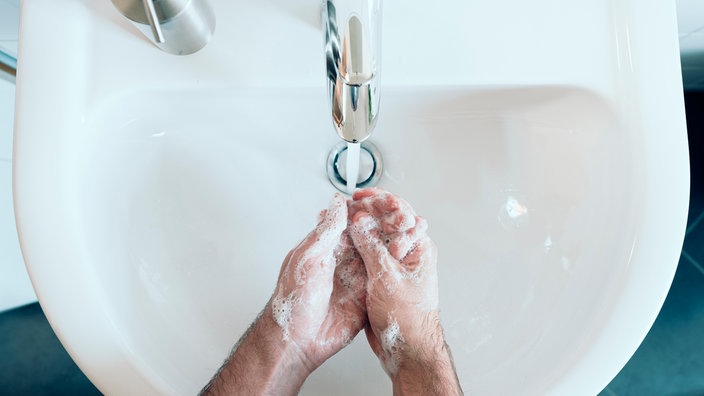 eingeseifte Hände über einem Waschbecken