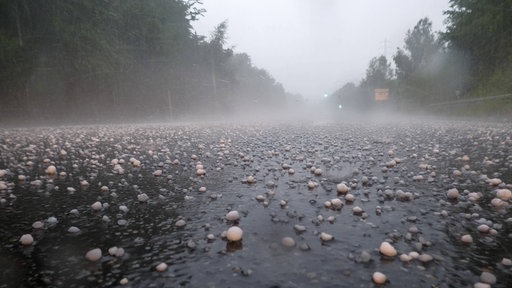 Hagelkörner so groß wie Tischtennisbälle liegen auf der Bundesstraße 59 bei Pulheim.