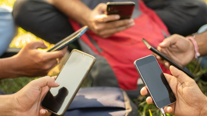 Schüler sitzen im Kreis und halten Smnartphones in den Händen