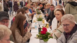 Menschen sitzen an einer Tafel beim Hansemahl in Münster 2024. 