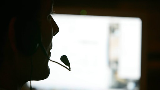 Ein Mann telefoniert per Headset vor einem Computerbildschirm