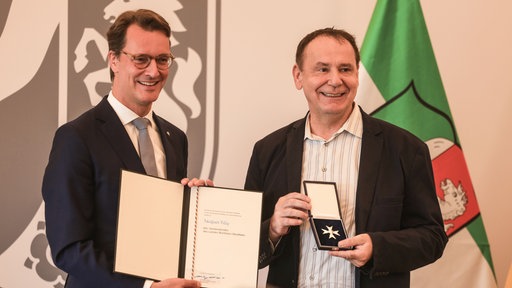 Hendrik Wüst und Jacques Tilly bei der Verleihung des Bundesverdienstordens