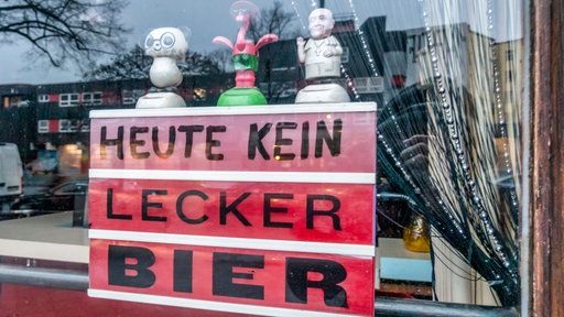 Ein Schild mit der Aufschrift "Heute kein lecker Bier" steht in einem Schaufenster in einer Berliner Kneipe.