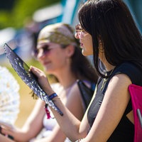 Zwei Frauen sitzen mit Fächern in der Hand in der Sonne 