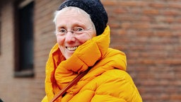 Monika Take-Hülsmann lächelt in die Kamera. Sie trägt einen langen Wintermantel.