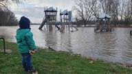 Ein Kind steht an einem überschwemmten Spielplatz