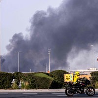Straße mit Autos und einer Rauchwolke im Hintergrund 