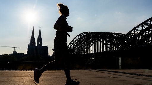 Eine Frau joggt am Kölner Rheinufer
