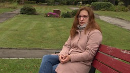 Eine Frau sitzt auf einer roten Bank