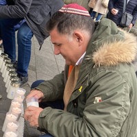 Ein Mann stellt eine Kerze vor der Düsseldorfer Synagoge auf.