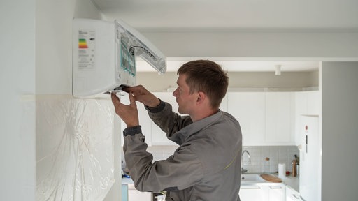 Ein Techniker repariert eine Klimaanlage in einer Wohnung