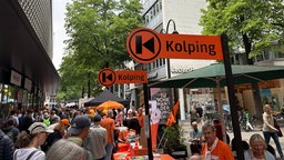 Passanten schauen sich die Stände von Kolping in der Kölner Innenstadt an. 