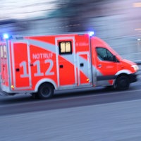 Ein Notarztwagen fährt mit Blaulicht über eine Hauptstraße.