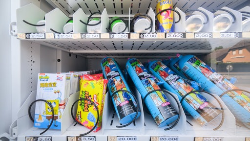 Ein Warenautomat, unter anderem mit Lachgasflaschen bestückt, steht vor einem Ladengeschäft.