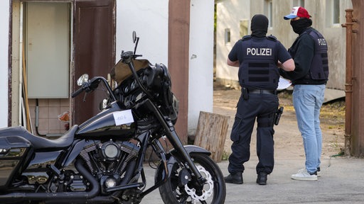 Ein Motorrad, das im Rahmen einer Razzia gegen die Rockergruppe Hells Angels von der Polizei beschlagnahmt wurde, steht vor einem Haus