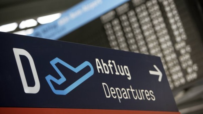Auf einem Schild wird in die Richtung gezeigt, wo es zum Abflug für die Fluggäste geht