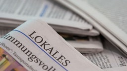 Eine Lokalzeitung wird über andere Zeitungen gehalten.