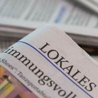Eine Lokalzeitung wird über andere Zeitungen gehalten.