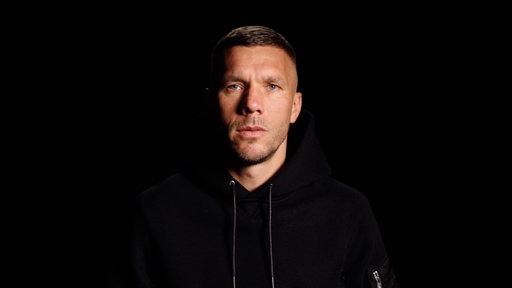 Lukas Podolski vor schwarzem Hintergrund
