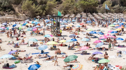 Viele Menschen liegen am Strand Cala Santanyi auf der Insel Mallorca.