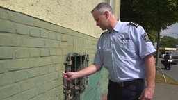 Polizist greift in Marode Mauer