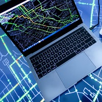 Laptop mit Straßennetzabbildung auf dem Monitor auf Leuchttisch mit Straßennetz.