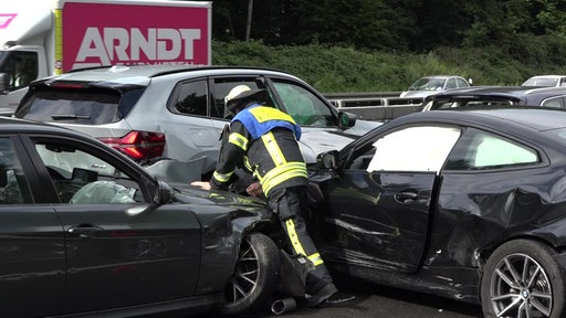 Eine Einsatzkraft steht zwischen zwei ineinandergefahren Autos 