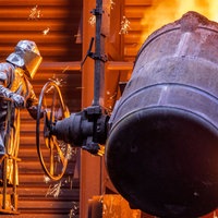 Arbeiter gießen flüssiges Eisen mit einer Temperatur von 1.400 Grad in einer Eisengießerei in vorbereitete Formen