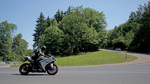 Ein Motorradfahrer fährt in der Eifel durch eine Kurve