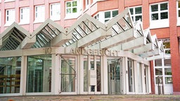 Im weißen Vorbau vor dem hohen, rot geklinkerten Hauptgebäude liegt die Schleuse zum Landgericht Münster.